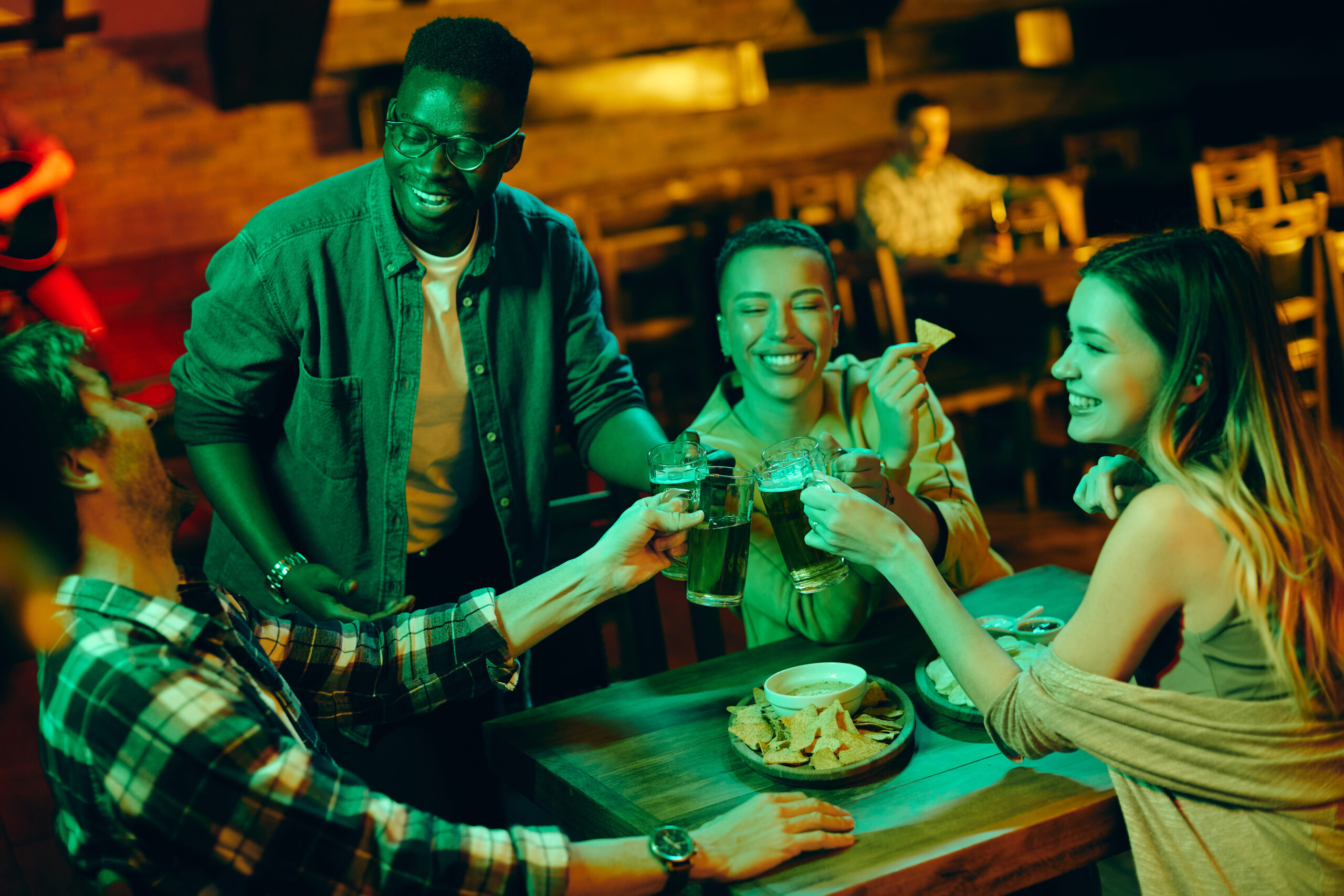 Multi-ethnic group of friends toast with beer and have fun while gathering in bar. Organisez votre soirée d'entreprise à Rouen